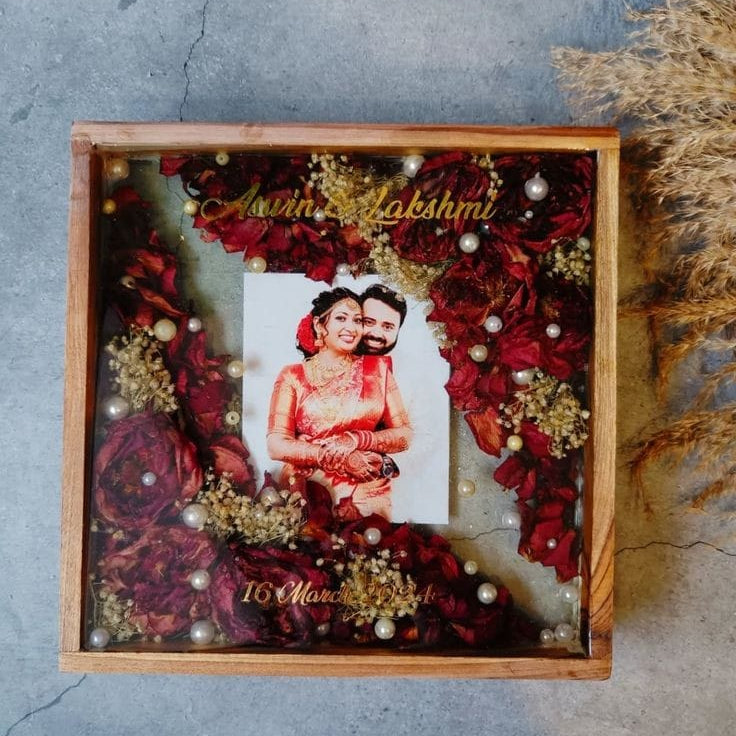 Decorative shadow box with flowers and a couple's photo on a textured surface